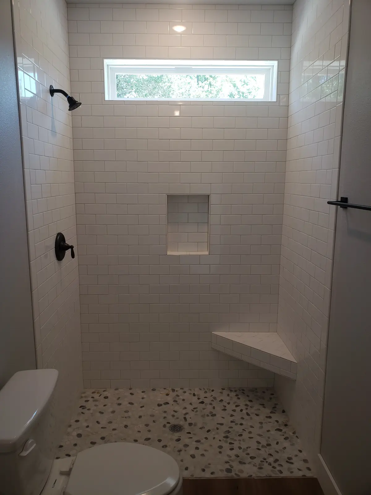 Subway tile shower with bench and mosaic floor